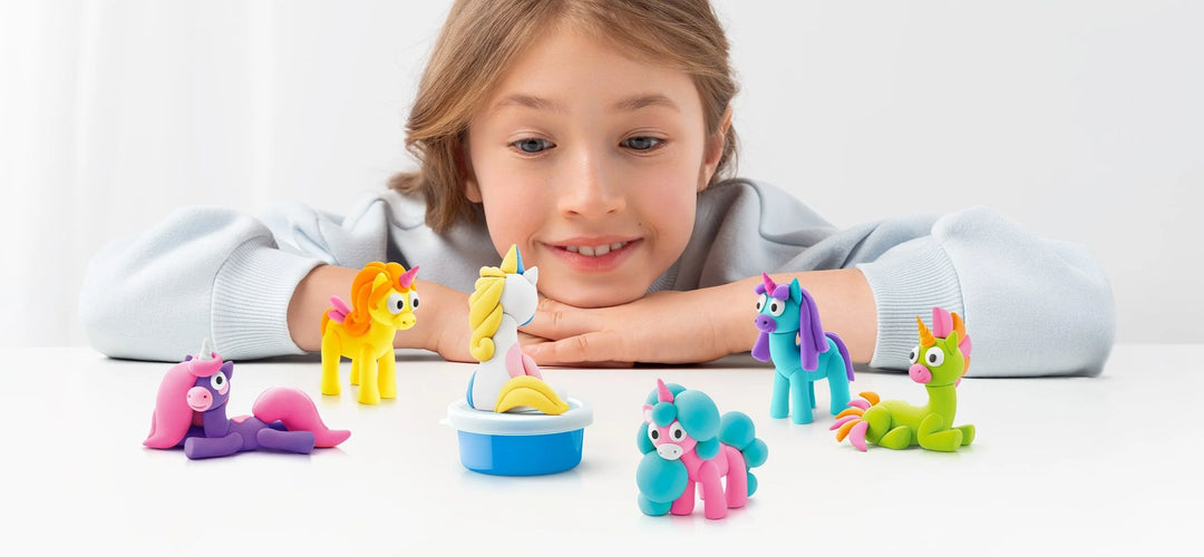 Child playing with colorful toy unicorns on a white surface