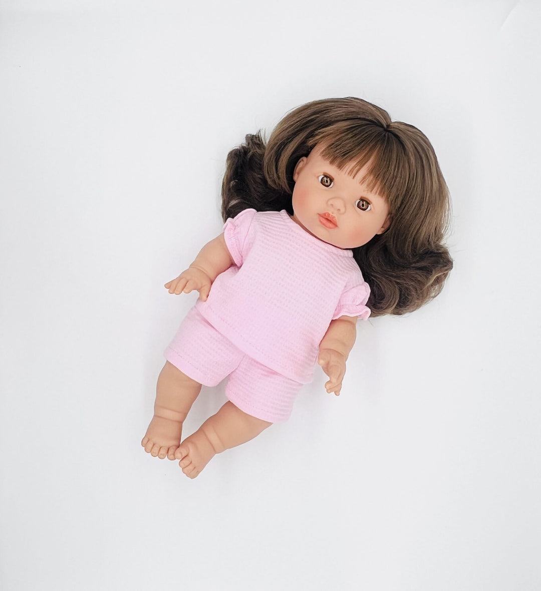 Doll wearing a pink outfit on a white background