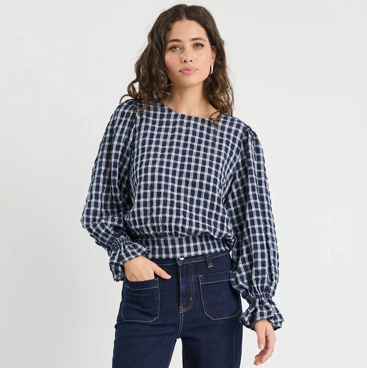 Woman wearing a checkered shirt and dark blue jeans on a white background