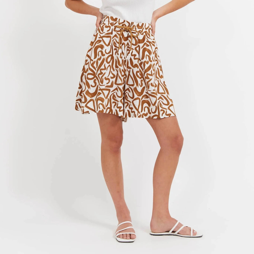 Woman wearing a white tank top and Haven patterned shorts on a white background