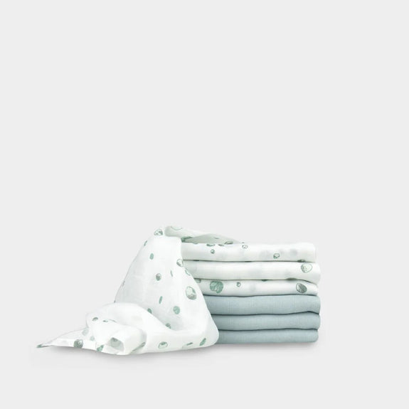 Stack of folded fabric with a white and green pattern on a light gray background