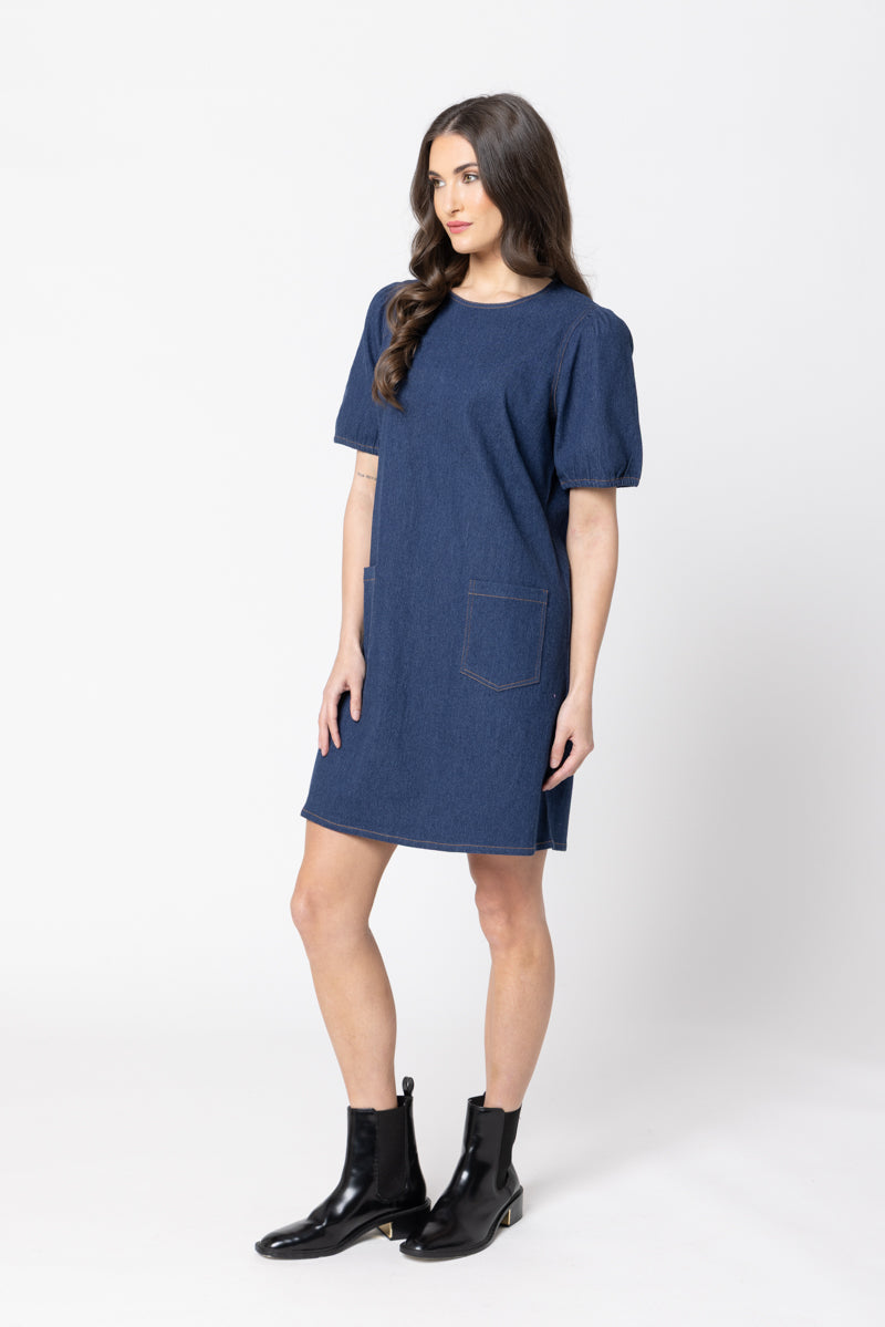 Woman wearing a Leila & Luca blue dress with a pocket on a white background