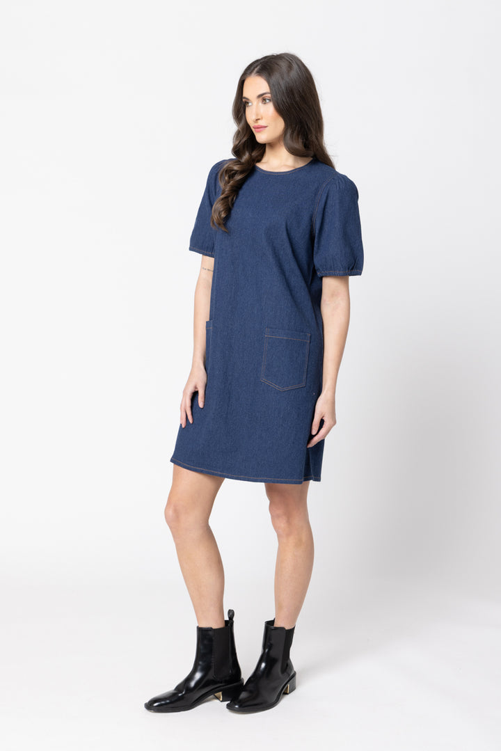 Woman wearing a Leila & Luca blue dress with a pocket on a white background