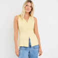 Woman wearing a yellow sleeveless top and blue jeans on a white background