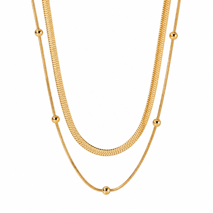 A gold-toned double-strand necklace featuring a textured snake chain and a finer chain with evenly spaced small spherical beads, displayed against a solid white background.