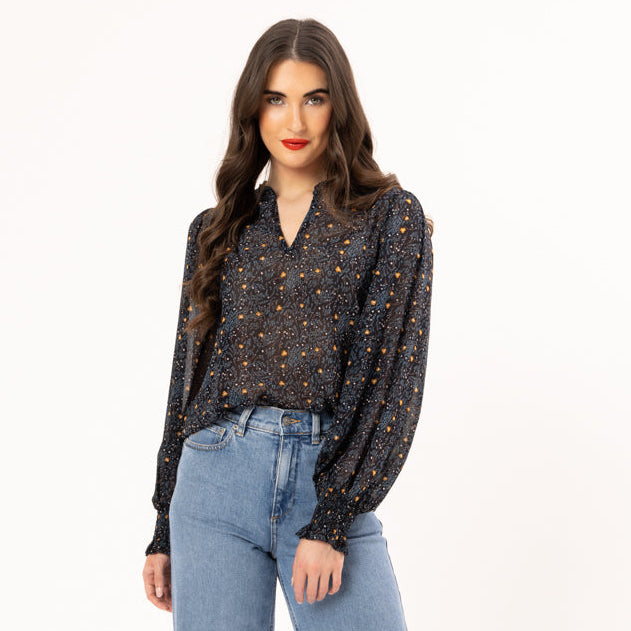 Woman wearing a patterned blouse and blue jeans on a white background
