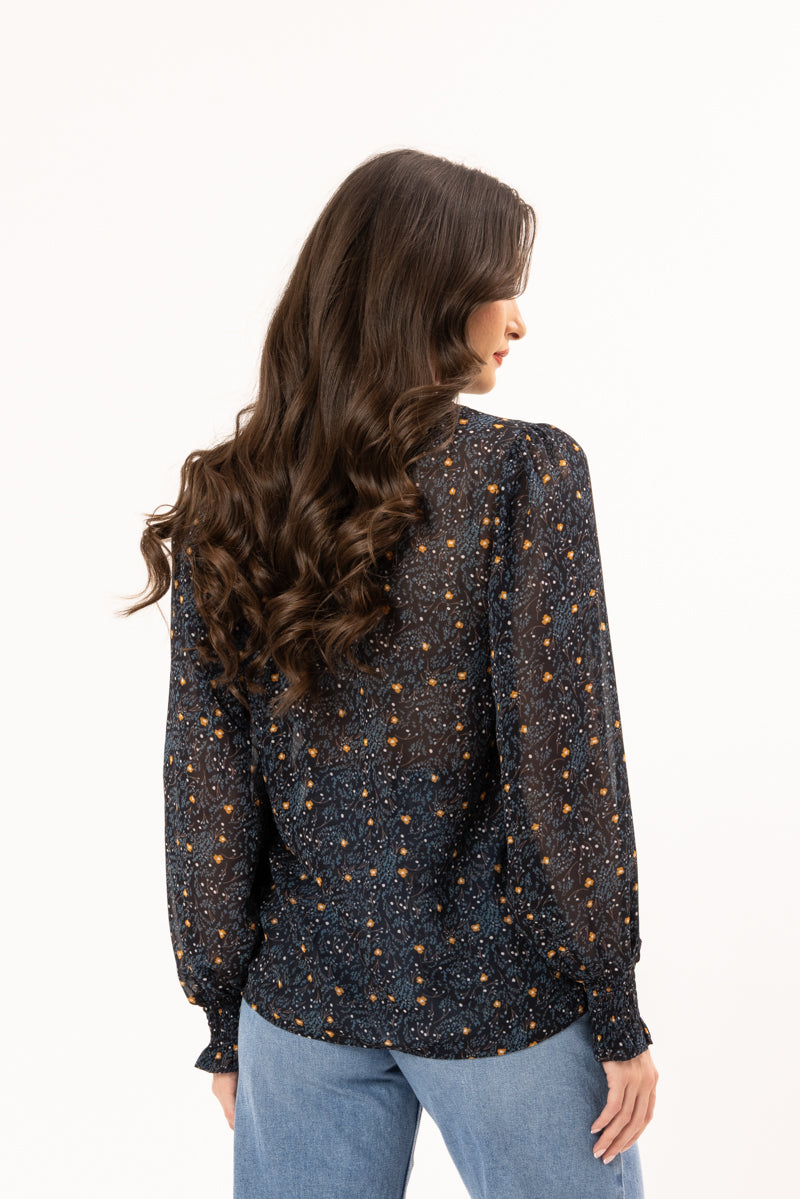 Woman wearing a patterned blouse and jeans on a white background