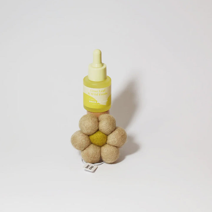 Yellow bottle with a dropper and beige flower-shaped object on a white background