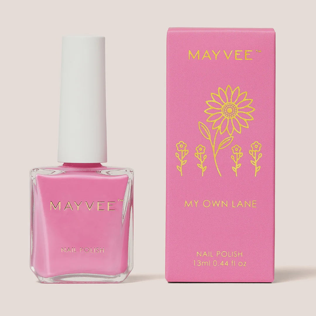 A bottle of Mayvee nail polish in the shade 'My Own Lane' next to its pink packaging box, both featuring gold floral designs and text, set against a solid light beige background.