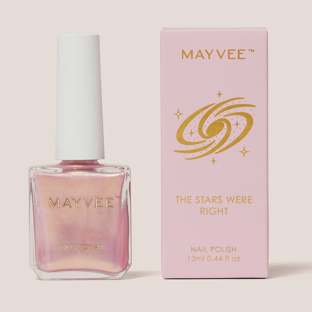 Mayvee nail polish in a clear glass bottle with a white cap, shown next to its light pink packaging box with gold lettering on a beige background.