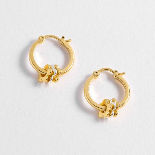Gold hoop earrings with floral designs on a light gray background