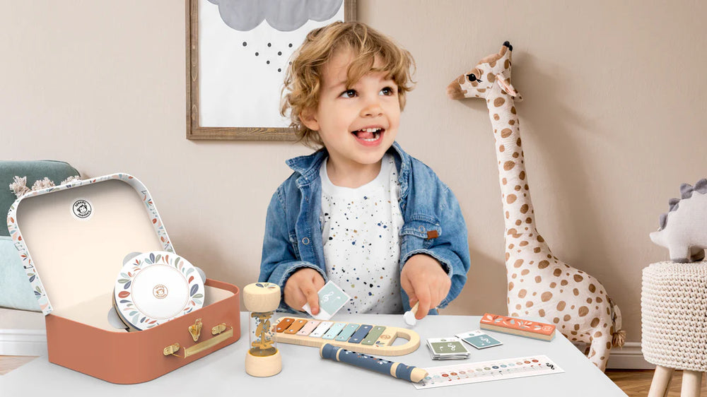 Child playing with a toy xylophone in a room with stuffed animals and decor.