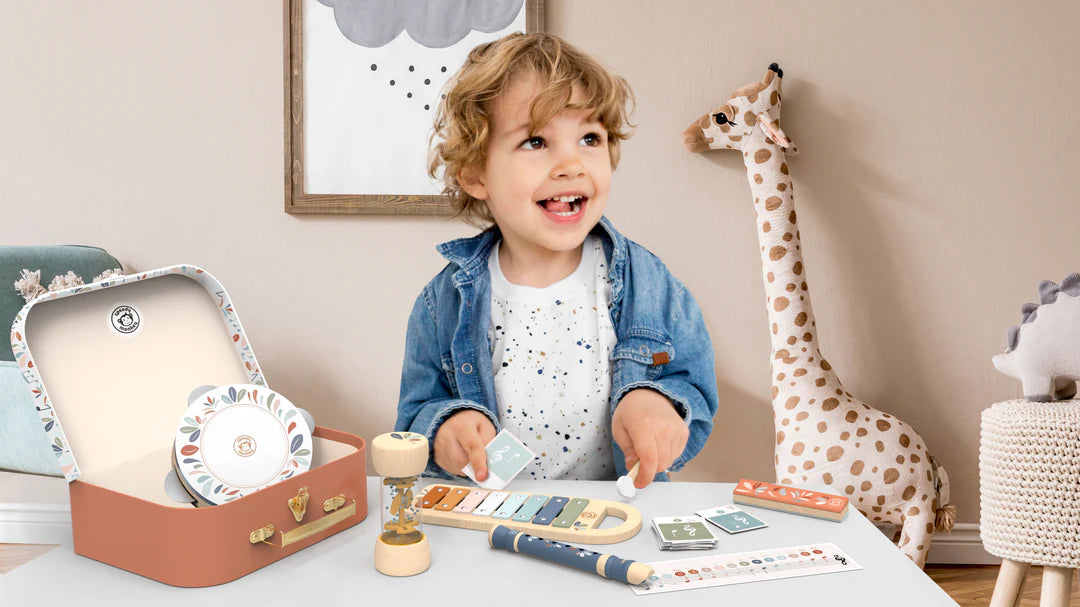 Child playing with a toy xylophone in a room with stuffed animals and decor.