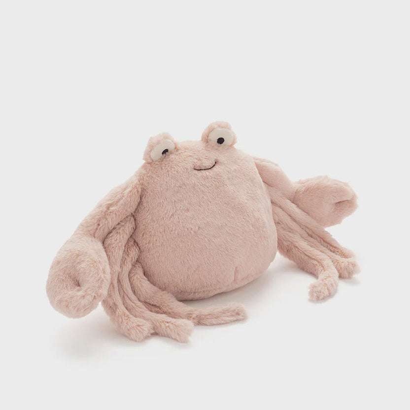 A soft plush octopus toy in a pale pink color, photographed against a clean, light gray studio background.