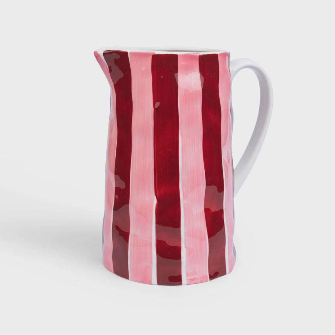 Ceramic pitcher with red and pink striped design on a white background