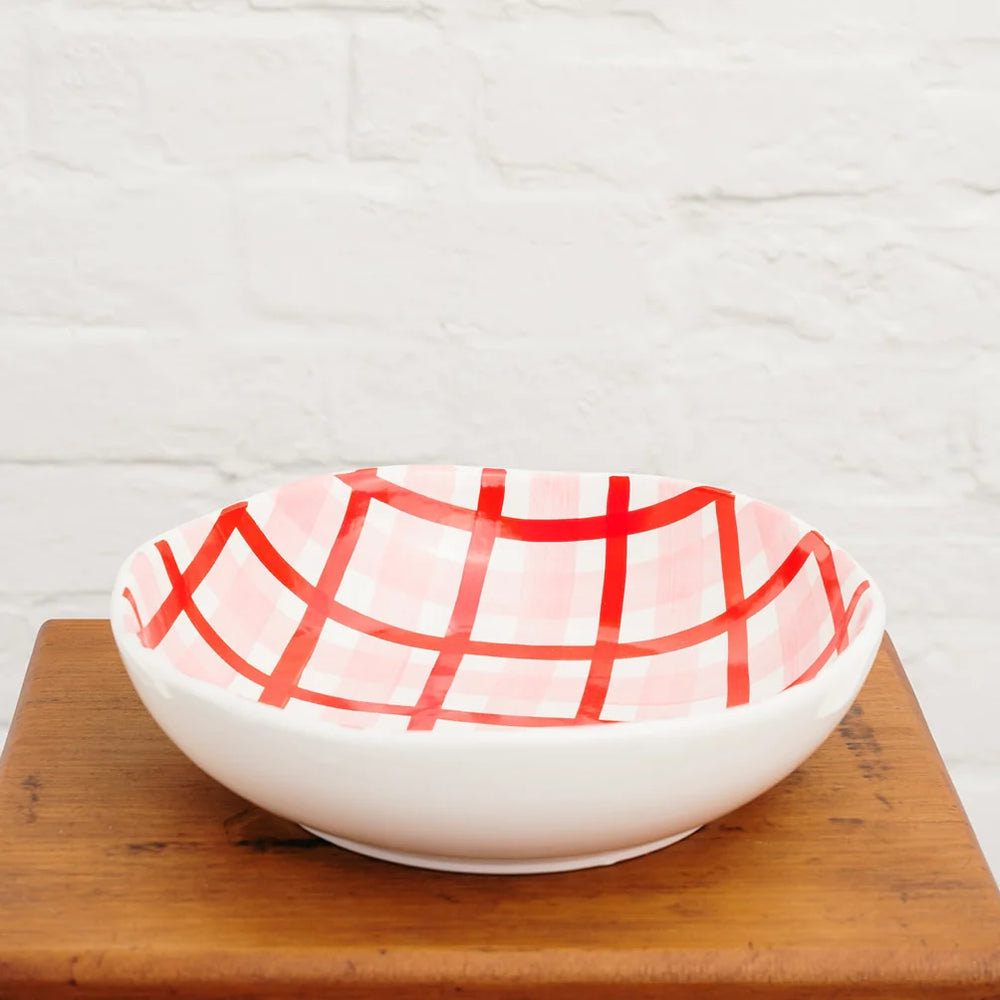 White bowl with red grid pattern on a wooden surface
