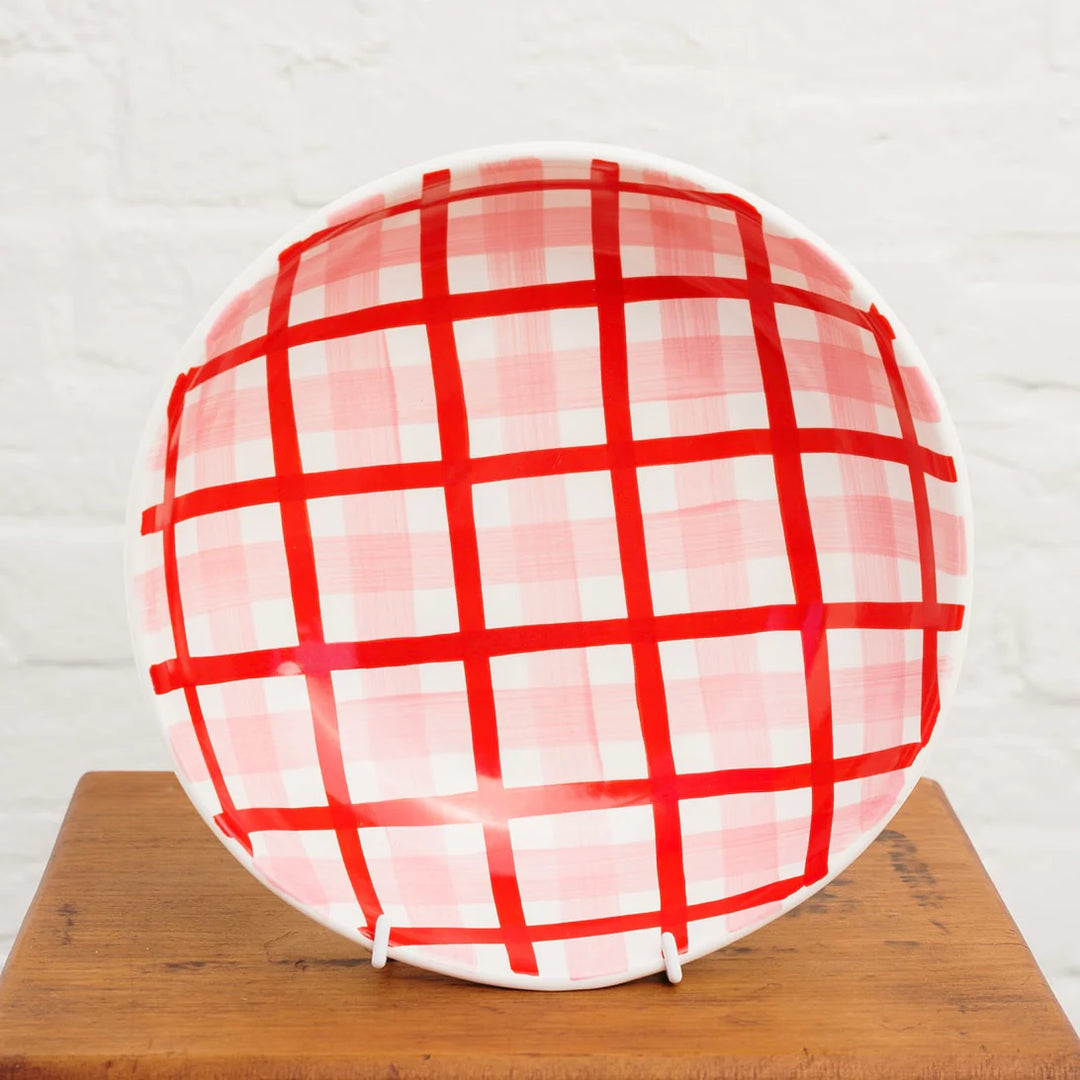 Roundnbowlwith red and white checkered pattern on a wooden surface.