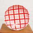 Roundnbowlwith red and white checkered pattern on a wooden surface.