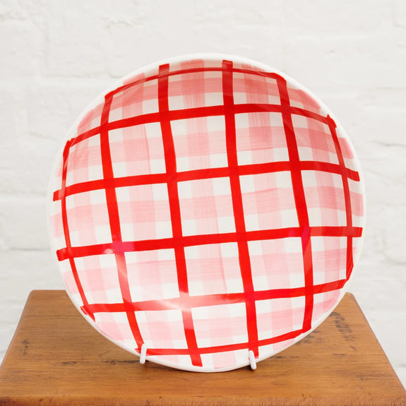 Roundnbowlwith red and white checkered pattern on a wooden surface.