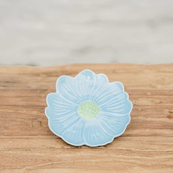 Ceramic flower-shaped dish with light blue petals and green center on a wooden surface