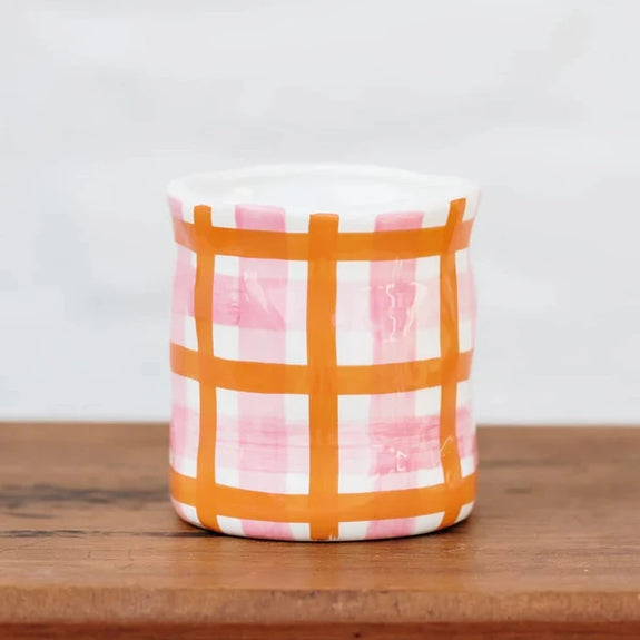 large candle with orange and pink checkered pattern on vessel