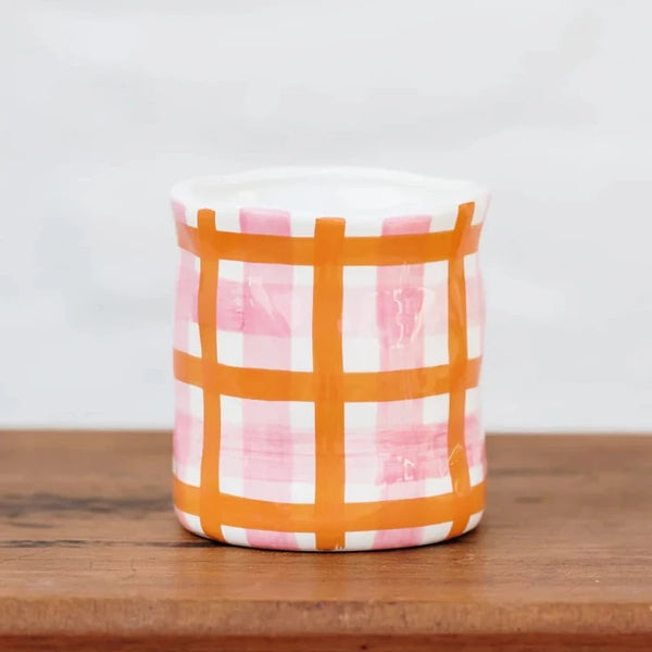 large candle with orange and pink checkered pattern on vessel
