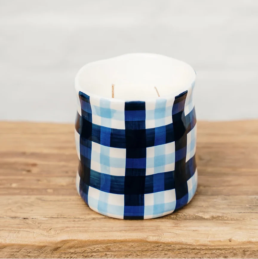 Candle with blue and white checkered pattern on a wooden surface