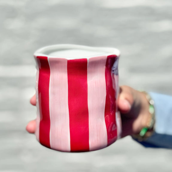 Red and white striped candle held by a person against a blurred background