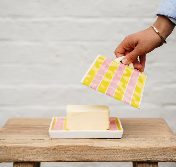 Person holding a colorful soap dish with a bar of soap on a wooden surface