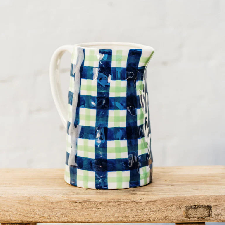 Ceramic pitcher with blue and green plaid pattern on a wooden surface