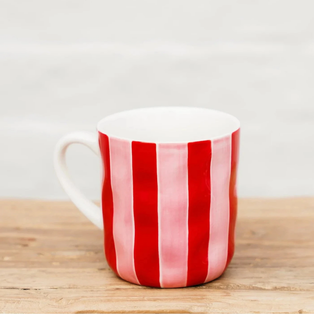 Red and white striped mug on a wooden surface with a light gray background