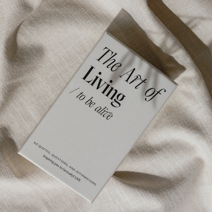 Book titled 'The Art of Living: To be alive' on a textured fabric surface