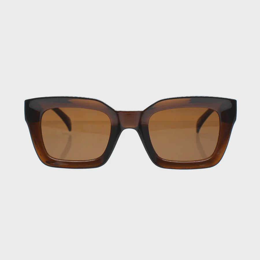 Oversized square sunglasses with a translucent dark brown acetate frame and warm brown tinted lenses, shown against a light gray background.