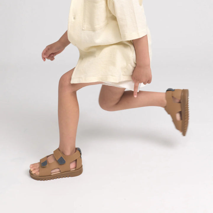 Child wearing brown pretty brave sandals on a white background