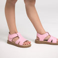 Pink pretty brave sandals with brown soles worn by a person on a white background