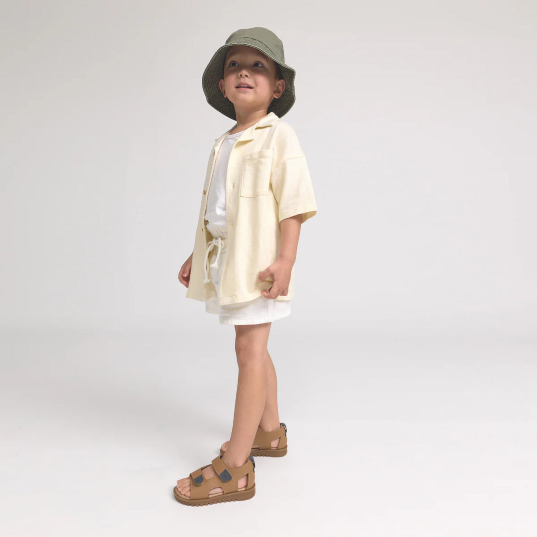 Child wearing a light-colored outfit with a hat on a white background