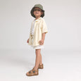 Child wearing a light-colored outfit with a hat on a white background