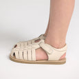 Beige pretty brave sandal worn on a foot against a plain background