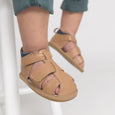 Tan children's sandals with velcro straps on a light background