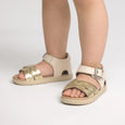 Pretty brave Children's sandals with gold and beige straps on a white background