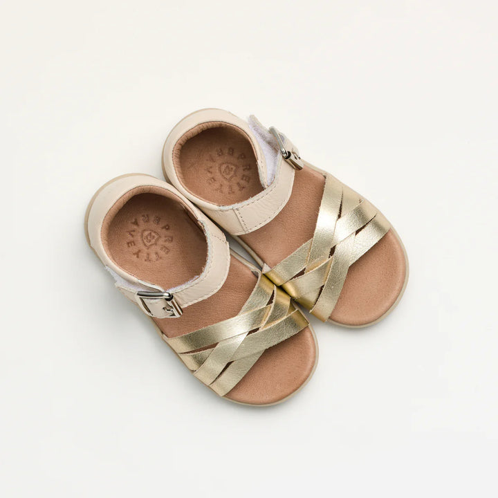 Pair of children's pretty brave sandals with gold straps on a light gray background
