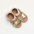 Pair of children's pretty brave sandals with gold straps on a light gray background