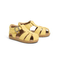 Pair of yellow pretty brave sandals with a buckle on a white background