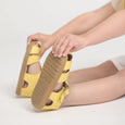 Yellow pretty brave sandals with brown soles held by a person on a light gray background