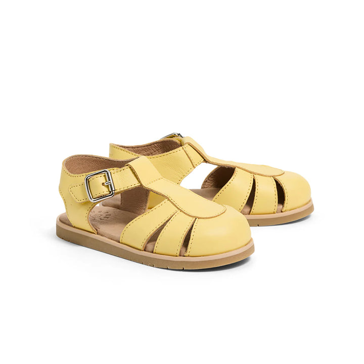 Pair of yellow pretty brave sandals with a buckle on a white background