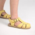 Yellow pretty brave sandals with a buckle on a light gray background