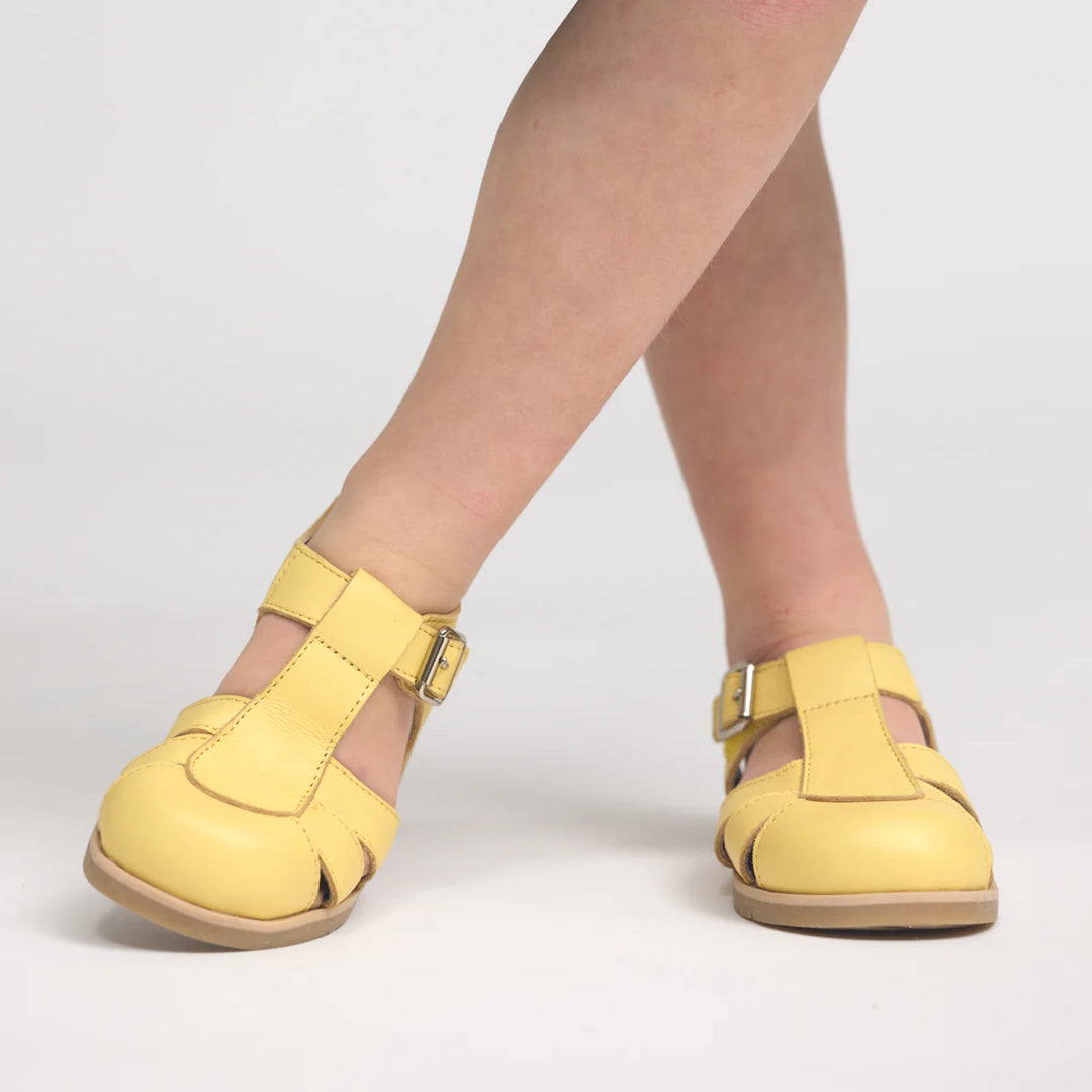 Yellow pretty brave shoes worn by a person on a light gray background