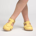 Yellow pretty brave shoes worn by a person on a light gray background