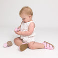 Baby wearing pink checkered pretty brave riley shoes on a white background