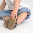 Child's hand holding a pretty brave sandal with a visible brand logo on a white background
